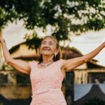 Elderly woman with arms outstretched.